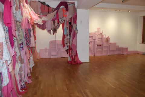 Title: Estranged (2022/2023) Solo Exhibition: Estranged Venue: Ballai Bana Gallery of Cultúrlann Mc Adam Ó Fiaich Belfast Medium: Mixed Media Installation with Textiles: Salvaged Drawers, salvaged bedframes, salvaged wood, deconstructed washing machines, deconstructed microwave, cooker, timber, paint, pipe fittings, empty flower pots, dishcloth, concrete house block, house bricks, recycled Plexiglas sheets, vacuum handle, floorboards, hand stitched textile from used women’s clothes. Dimensions: L:23 ft (by 